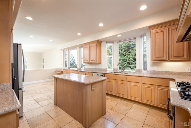 kitchen featuring light brown cabinets, wall chimney range hood, recessed lighting, freestanding refrigerator, and a sink