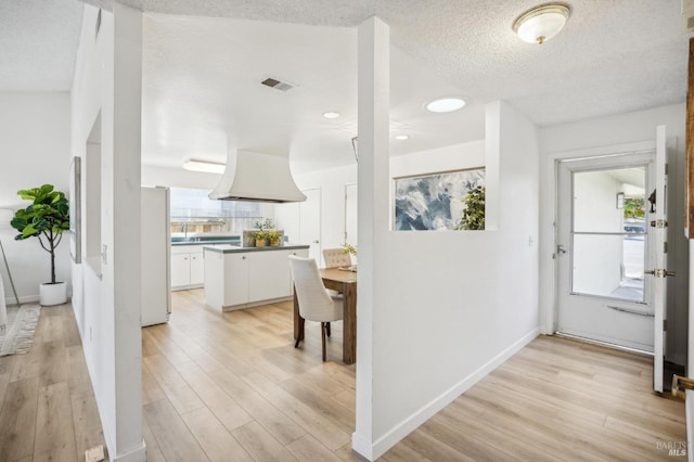 interior space with white cabinets, fridge, island range hood, and plenty of natural light