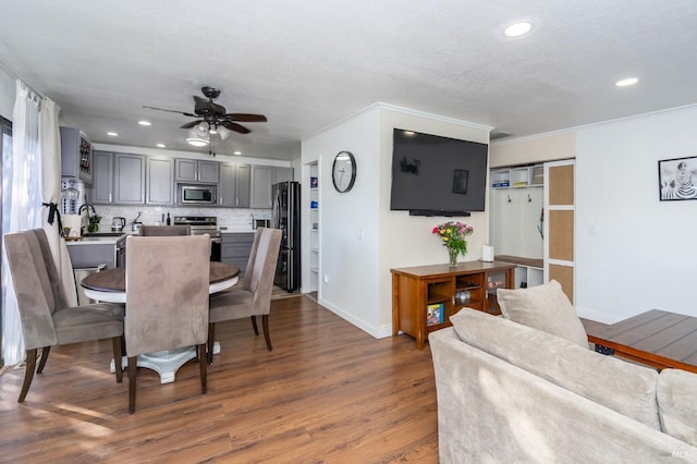 dining area featuring ceiling fan, dark wood-type flooring, crown molding, and a textured ceiling