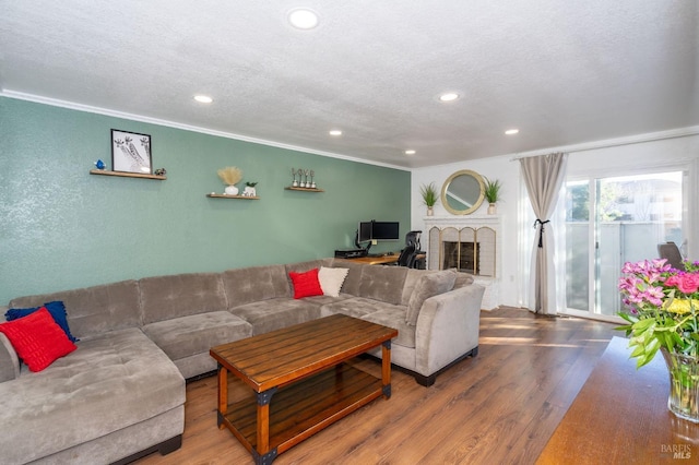 living room featuring ornamental molding, a textured ceiling, a fireplace, and wood-type flooring