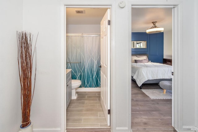 bathroom featuring toilet, a shower, vanity, and hardwood / wood-style flooring