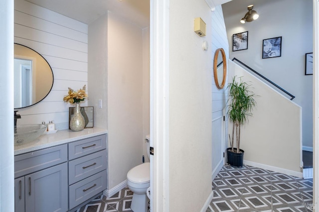 bathroom featuring toilet, wooden walls, and vanity