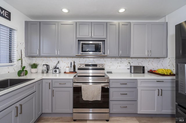 kitchen featuring appliances with stainless steel finishes, gray cabinetry, and decorative backsplash