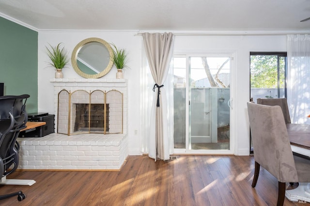 interior space with a brick fireplace, crown molding, and dark hardwood / wood-style flooring