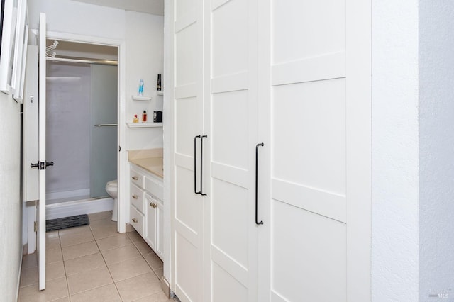 bathroom with toilet, an enclosed shower, tile patterned flooring, and vanity