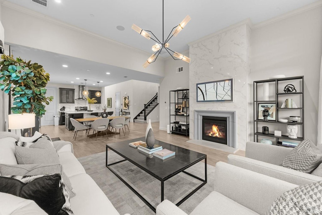 living room featuring a premium fireplace, ornamental molding, light hardwood / wood-style floors, and a high ceiling