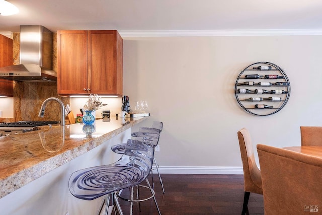 kitchen with backsplash, stove, dark wood-type flooring, wall chimney range hood, and ornamental molding