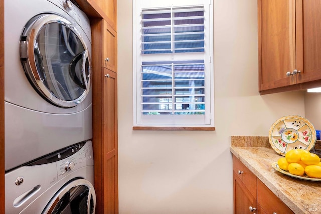 laundry area featuring stacked washer and clothes dryer and cabinets