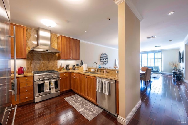 kitchen featuring stainless steel appliances, backsplash, ornamental molding, wall chimney exhaust hood, and sink