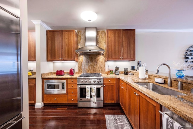 kitchen featuring wall chimney range hood, sink, built in appliances, ornamental molding, and light stone counters