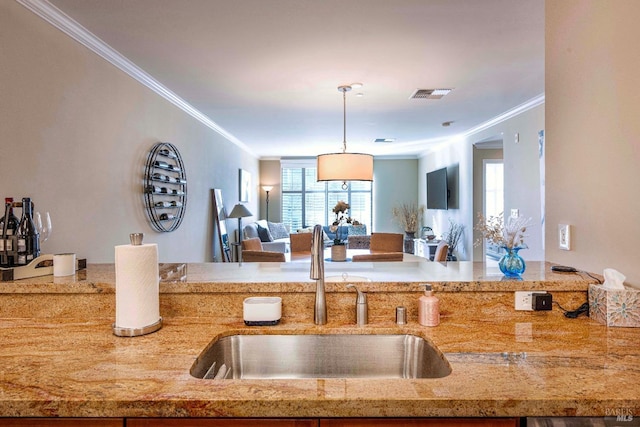 kitchen featuring crown molding, light stone counters, hanging light fixtures, and sink