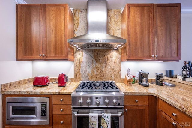 kitchen with light stone counters, wall chimney range hood, and stainless steel appliances