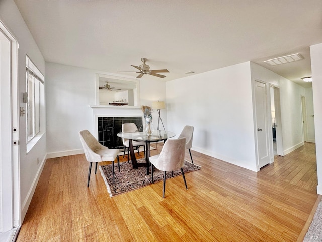 dining room with ceiling fan, hardwood / wood-style flooring, and a tile fireplace