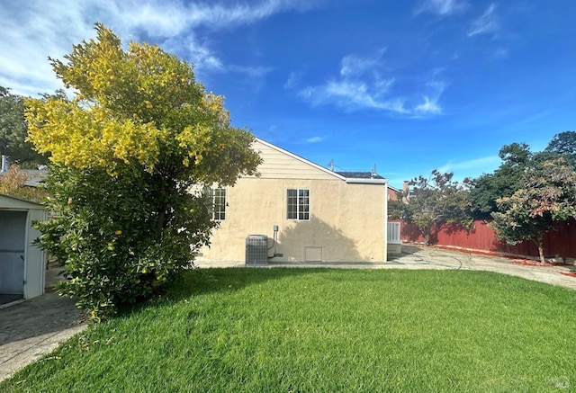 back of property with central air condition unit and a yard