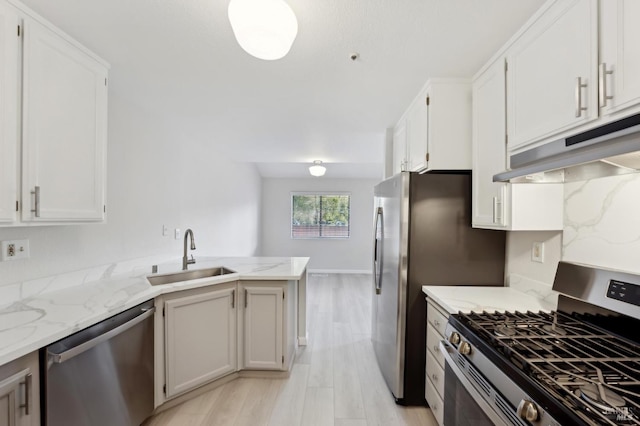 kitchen featuring sink, white cabinets, light stone counters, kitchen peninsula, and appliances with stainless steel finishes