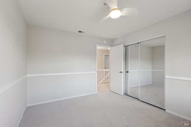 unfurnished bedroom with light carpet, a closet, and ceiling fan