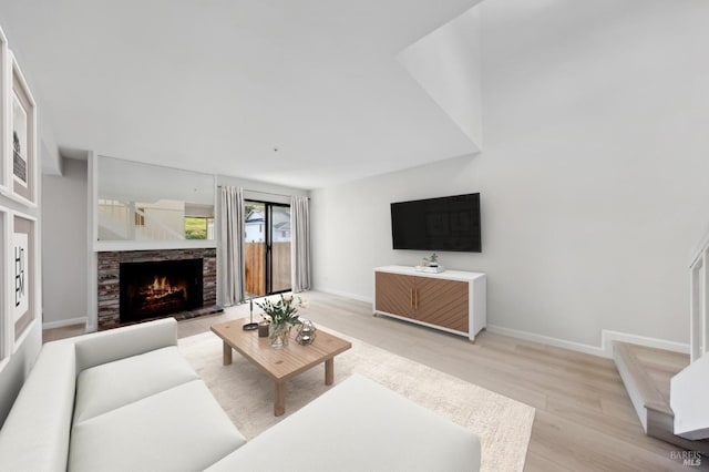 living room featuring light hardwood / wood-style floors and a stone fireplace