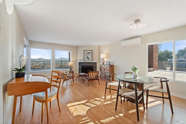 dining room with a fireplace, a wall unit AC, and light hardwood / wood-style floors