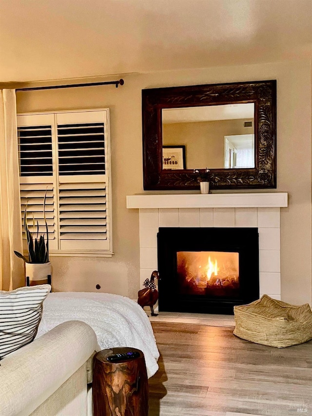 bedroom featuring a tiled fireplace and hardwood / wood-style flooring