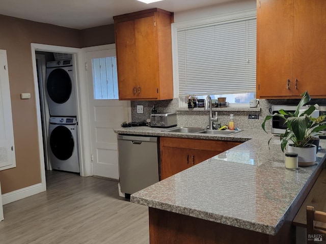 kitchen featuring sink, dishwasher, tasteful backsplash, light hardwood / wood-style flooring, and stacked washer and clothes dryer