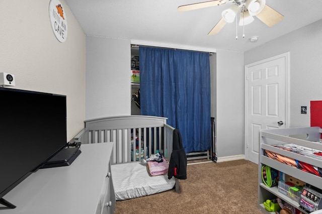 carpeted bedroom with ceiling fan and a crib