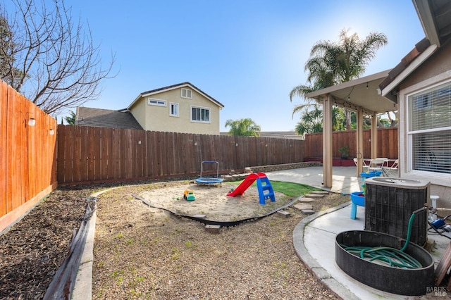 view of yard with a trampoline, central AC, and a patio area