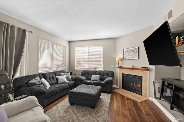 living room featuring a tiled fireplace and dark hardwood / wood-style flooring