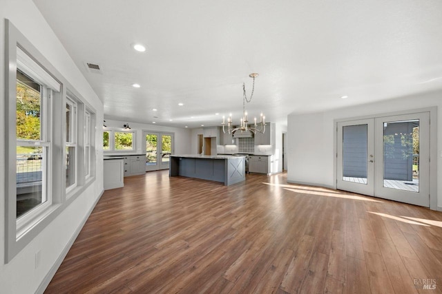 kitchen with a kitchen island with sink, french doors, a chandelier, and hanging light fixtures