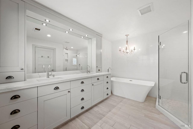 bathroom with hardwood / wood-style floors, separate shower and tub, an inviting chandelier, and vanity