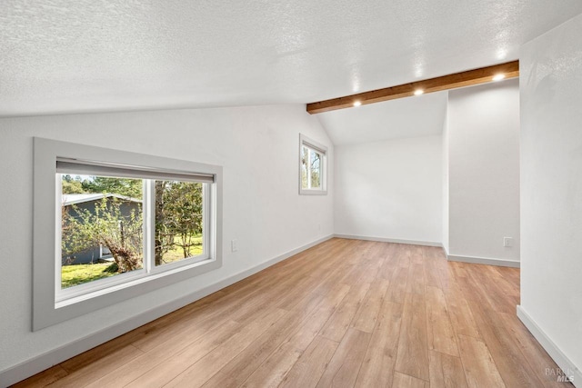 unfurnished room featuring a textured ceiling, vaulted ceiling with beams, and plenty of natural light