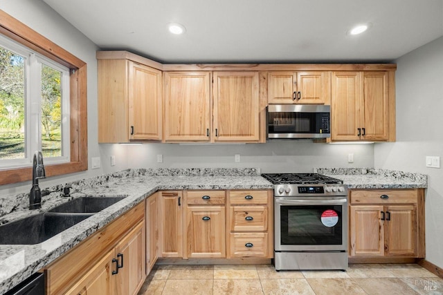 kitchen featuring light stone countertops, appliances with stainless steel finishes, light brown cabinets, and sink