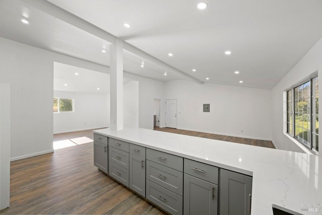 kitchen with light stone countertops, gray cabinets, a healthy amount of sunlight, and vaulted ceiling with beams