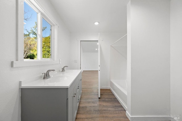 bathroom featuring vanity, hardwood / wood-style floors, and a bath