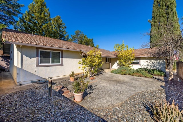 ranch-style home with a patio area, a tiled roof, and stucco siding