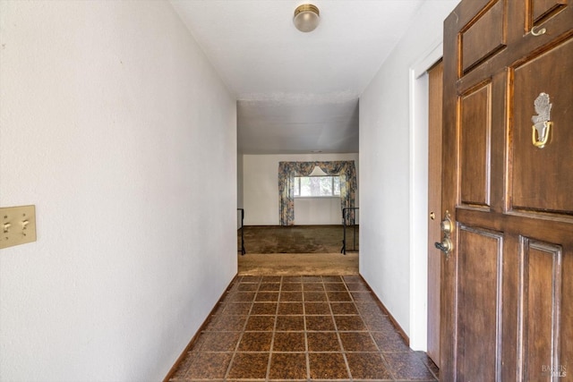 hall with dark colored carpet