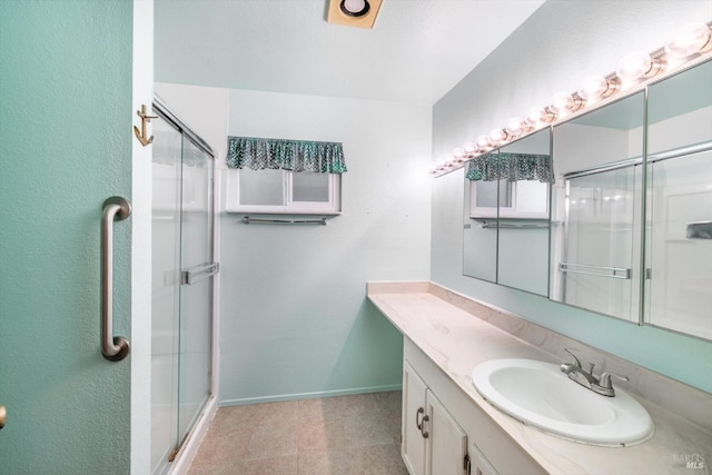 full bathroom featuring a stall shower, baseboards, and vanity