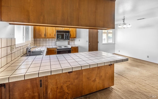 kitchen featuring decorative light fixtures, tile counters, brown cabinetry, range with electric cooktop, and black microwave