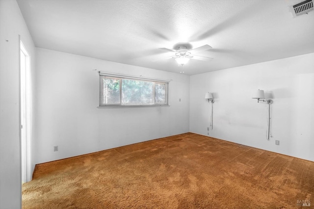 empty room featuring ceiling fan, a textured ceiling, carpet, and visible vents