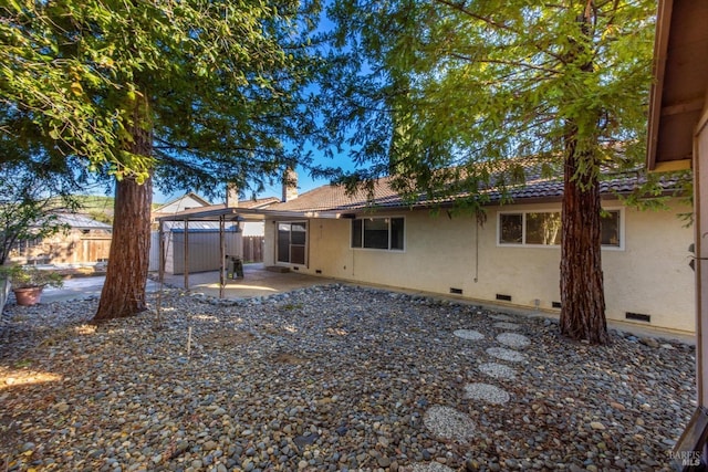 back of property featuring a tile roof, stucco siding, crawl space, a patio area, and fence