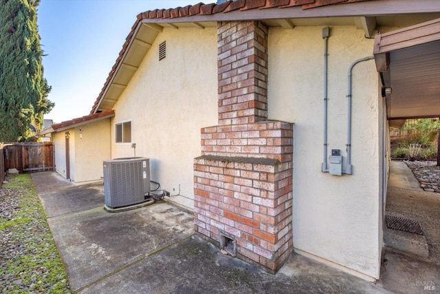 view of property exterior with central AC unit, a patio area, brick siding, and stucco siding