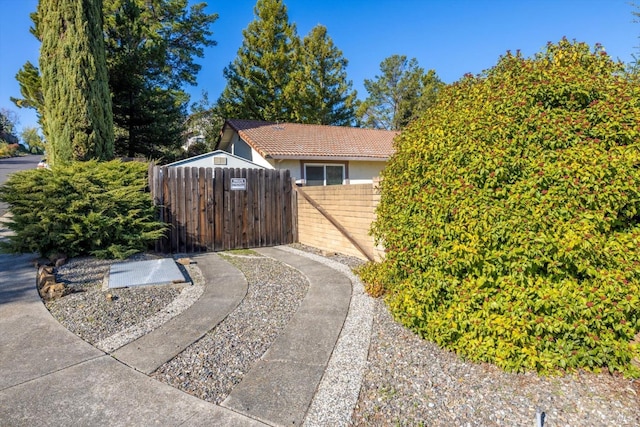 view of side of property featuring a tile roof, fence, and a gate