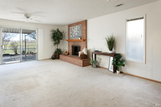 carpeted living room featuring a textured ceiling, a brick fireplace, and ceiling fan