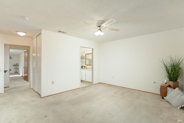 spare room featuring ceiling fan, a textured ceiling, and light carpet