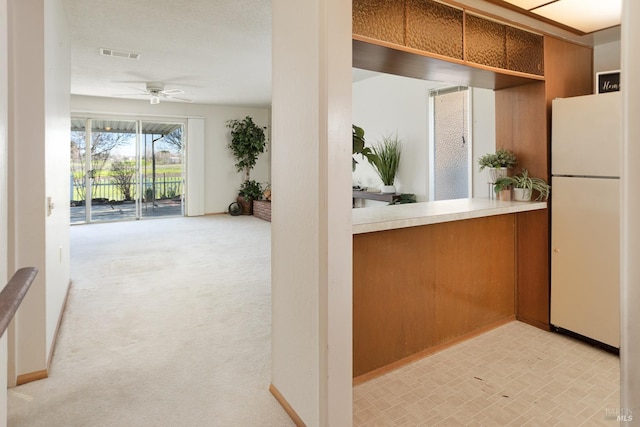 kitchen featuring light carpet, ceiling fan, and white refrigerator