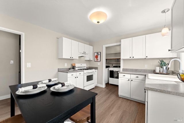 kitchen featuring hanging light fixtures, light wood-type flooring, white gas range oven, sink, and white cabinetry