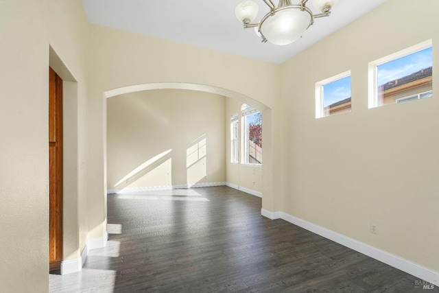 empty room featuring an inviting chandelier and dark hardwood / wood-style flooring