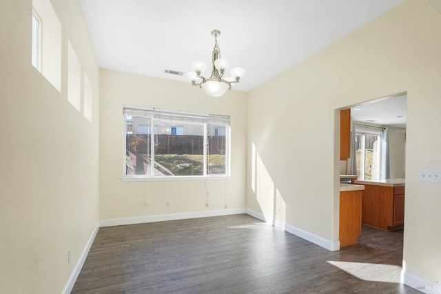 unfurnished dining area with a chandelier and dark hardwood / wood-style flooring