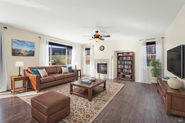 living room featuring ceiling fan, dark hardwood / wood-style floors, and a tile fireplace