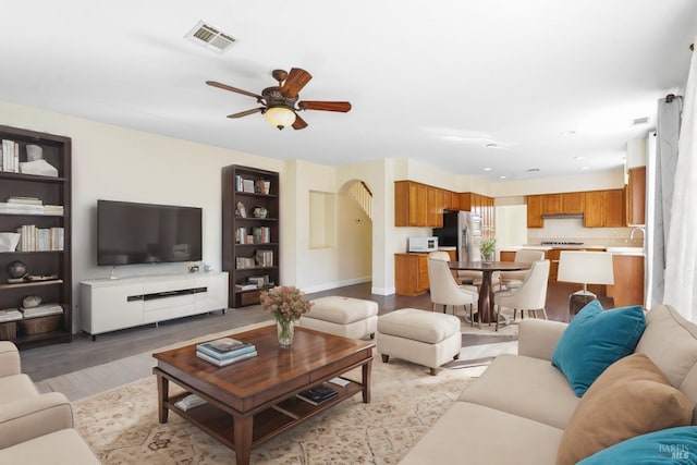 living room featuring ceiling fan, sink, and light wood-type flooring