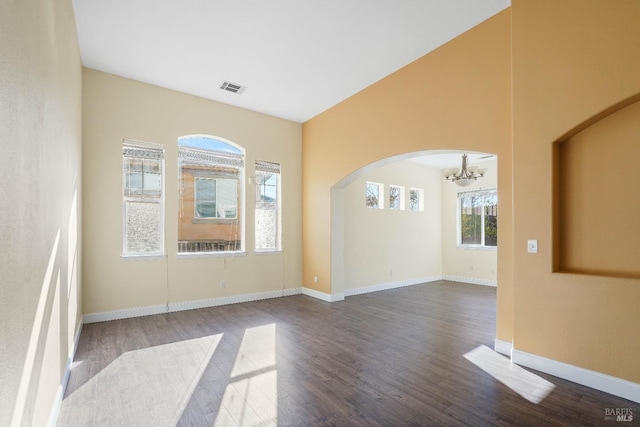 unfurnished room with an inviting chandelier, a wealth of natural light, and wood-type flooring